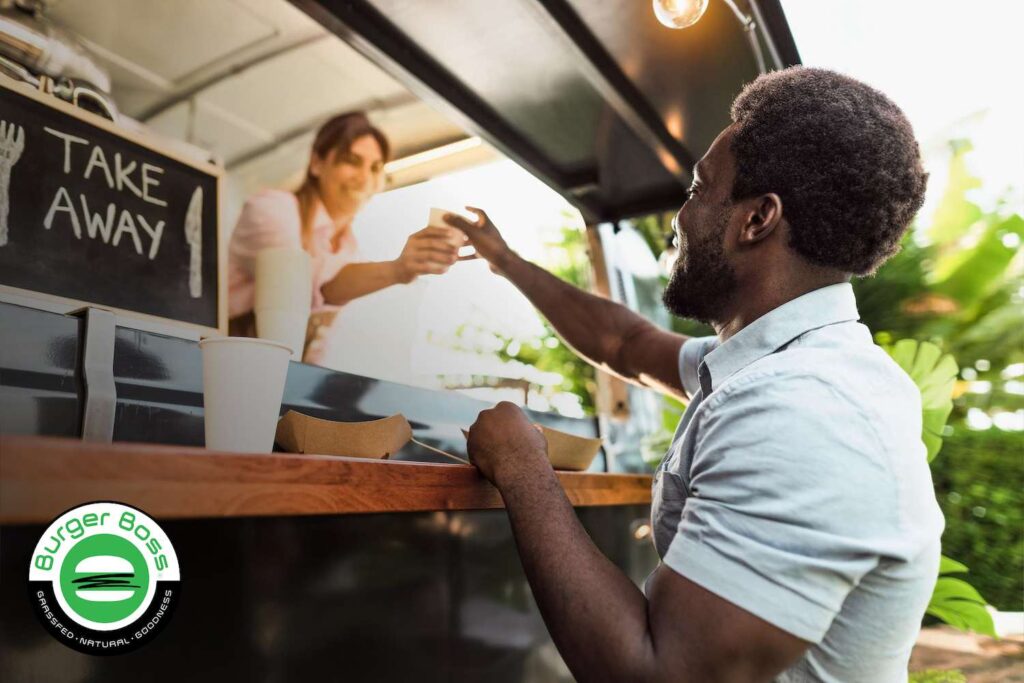 young man orders burger from food truck